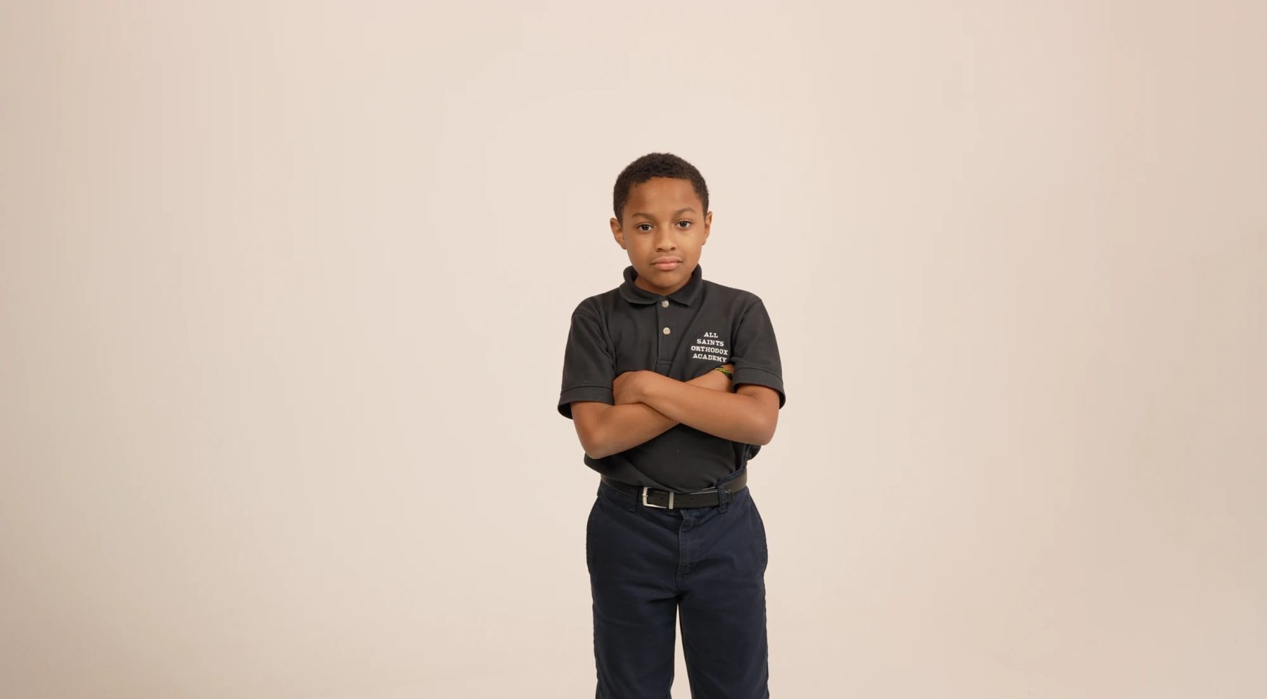 An All Saints student in a school polo, arms crossed, looking at the camera