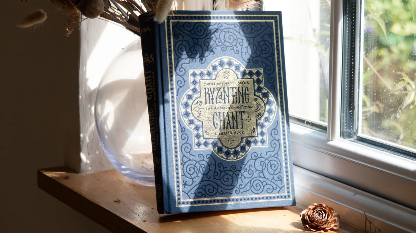 A Byzantine chant book open on a stand in window light