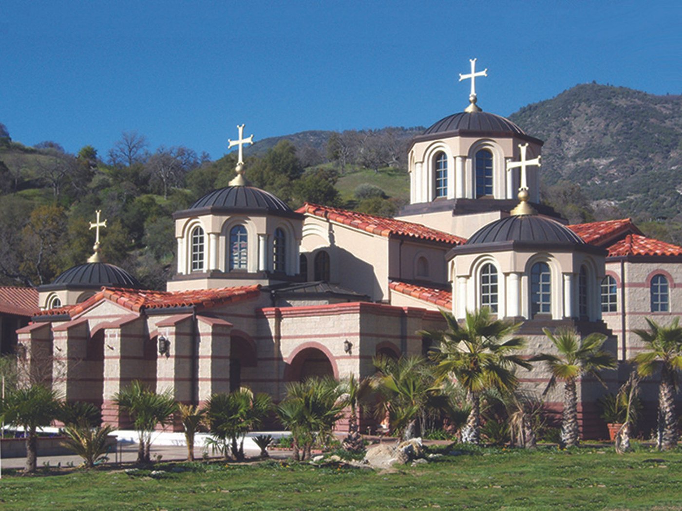 The domes and gold crosses of Holy Theotokos of the Lifegiving Spring Monastery against the Sierra foothills in Dunlap, California