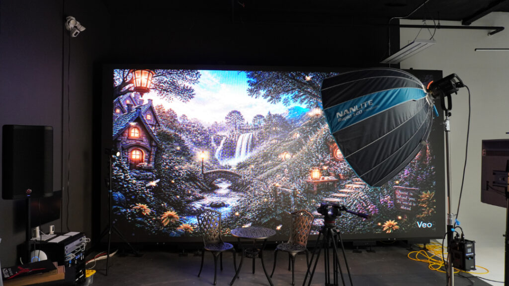 A wall-sized LED screen showing a painted landscape, lit by a softbox on a stand, in the Greek Fire Studios sound stage