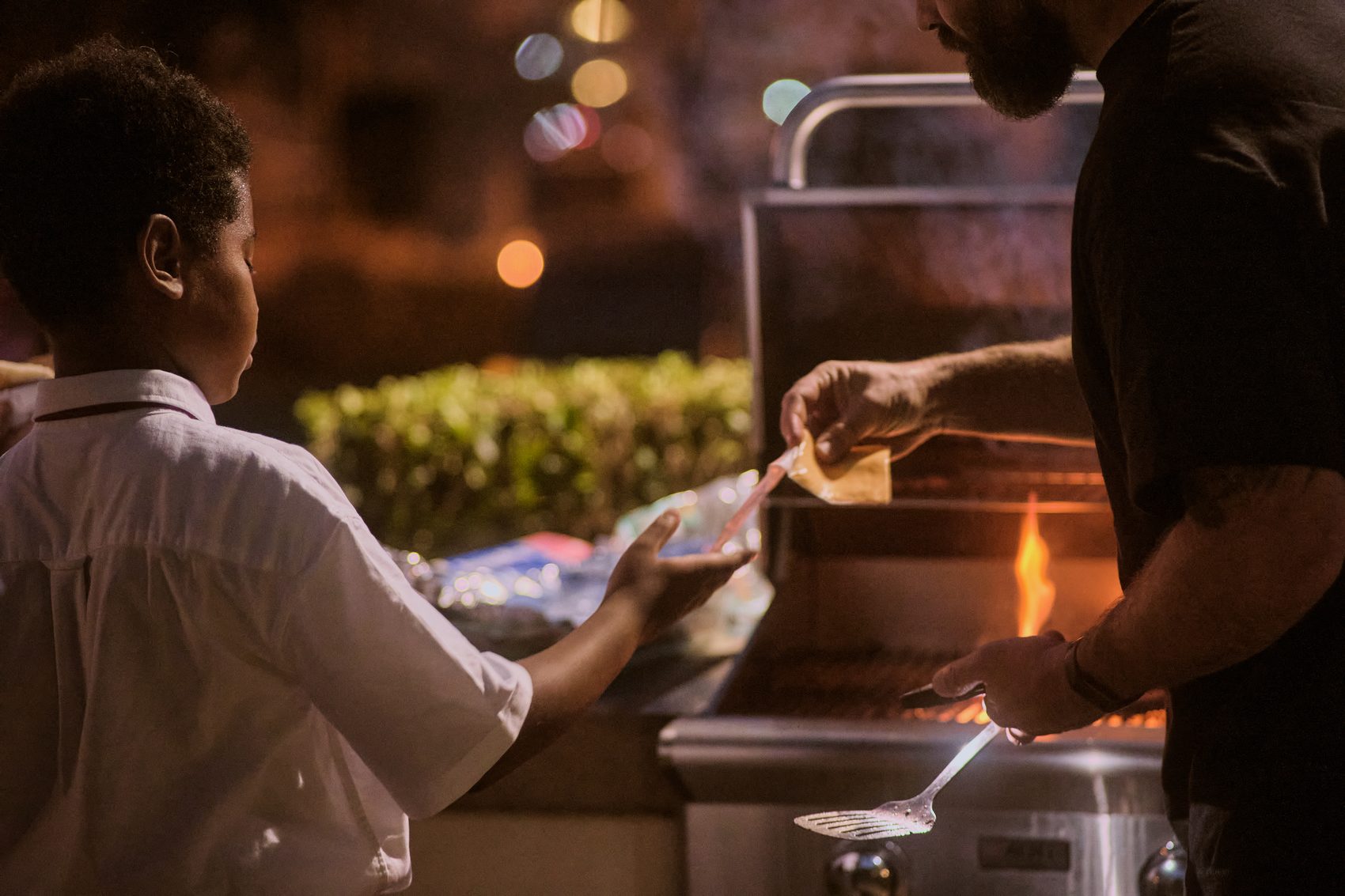 A student holding a plate at the serving line, lit by the grill