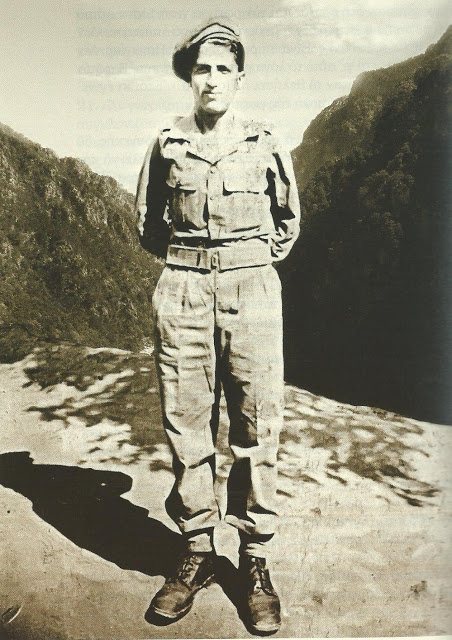 St. Paisios as a young soldier, standing in uniform on a mountain road